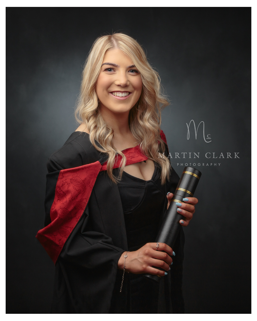 Graduation portrait of young woman with gown and scroll