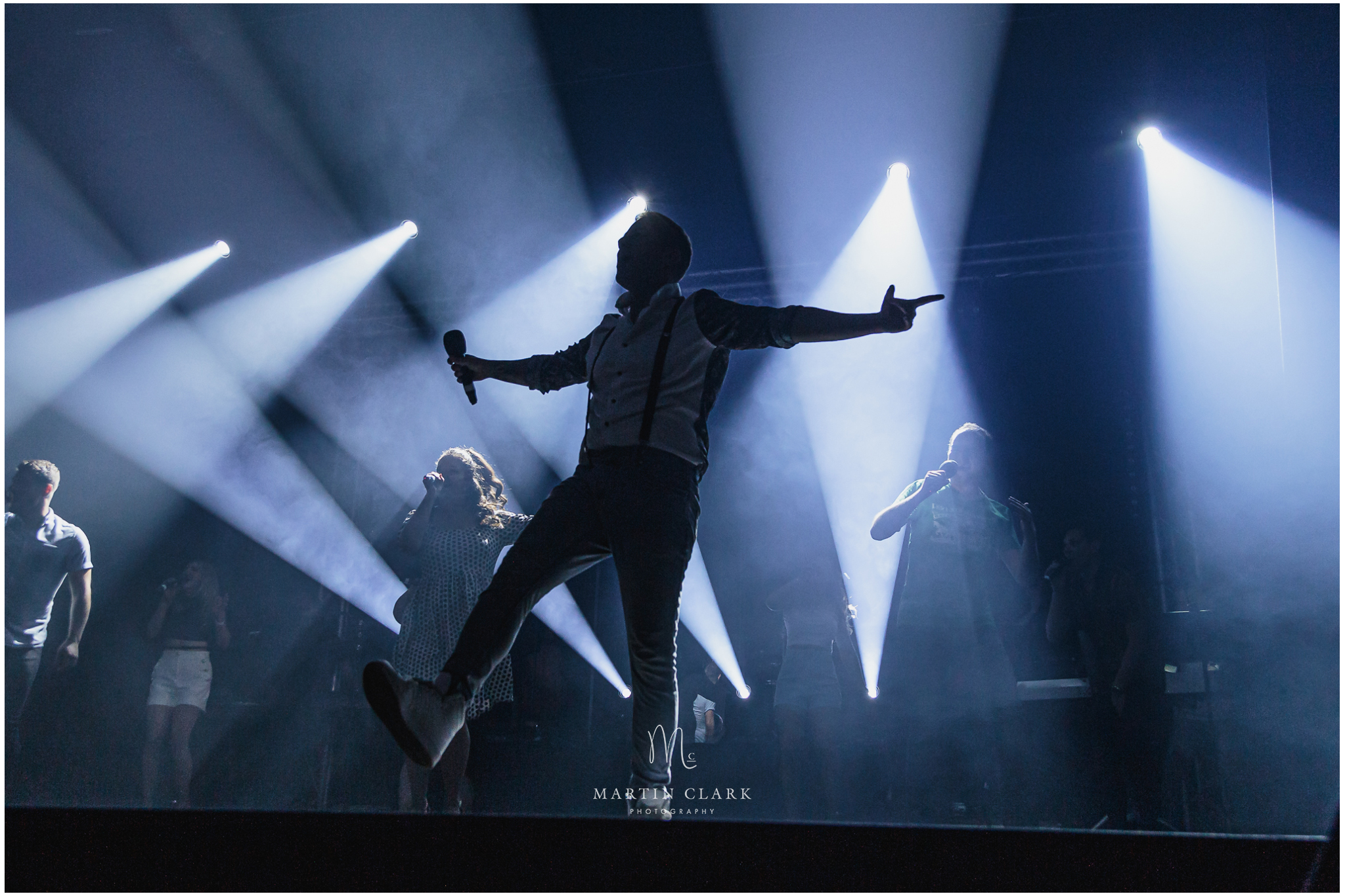 Backlit singer performing on theatre stage with stage lighting
