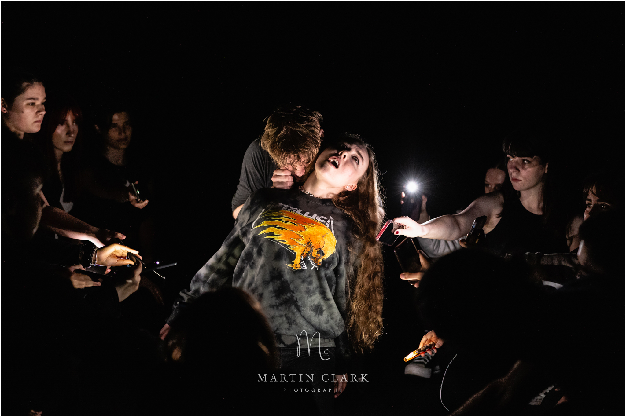 Cast from Royal Conservatoire of Scotland dramatically lit by mobile phone lights in a vampire blood sucking pose