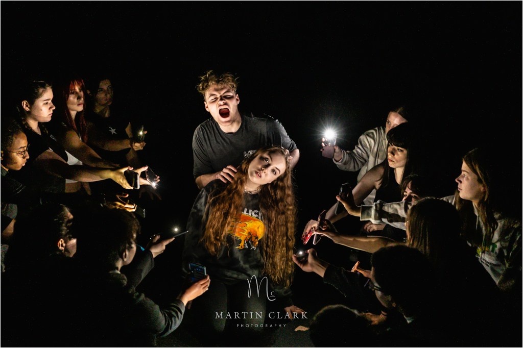 Cast from Royal Conservatoire of Scotland dramatically lit by mobile phone lights in a vampire pose
