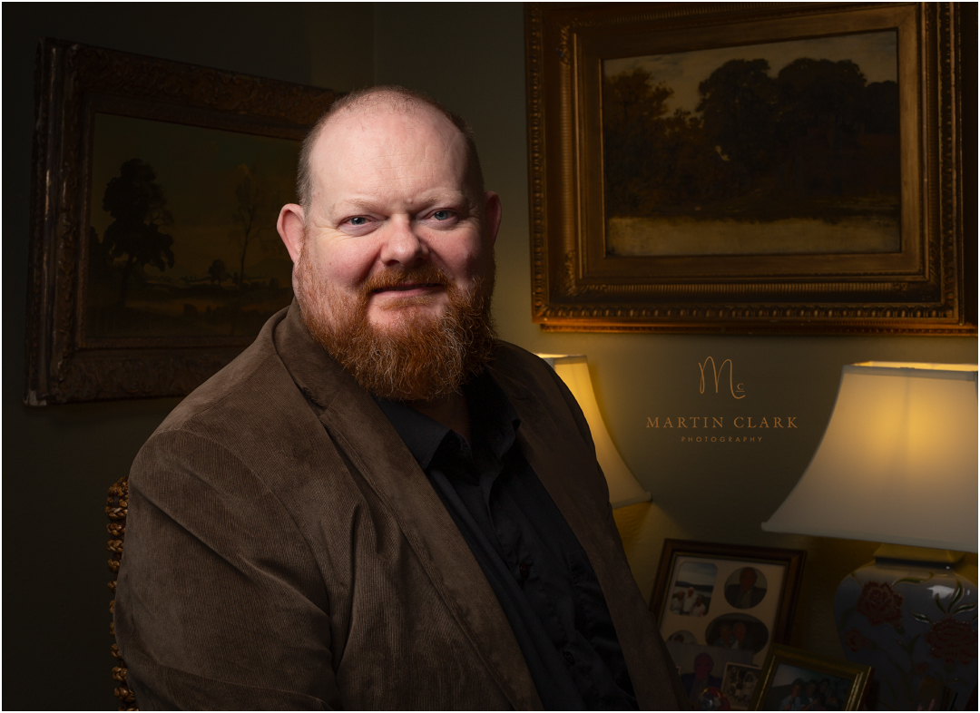 Business headshot for company CEO in his home office surrounded by oil paintings and family photos