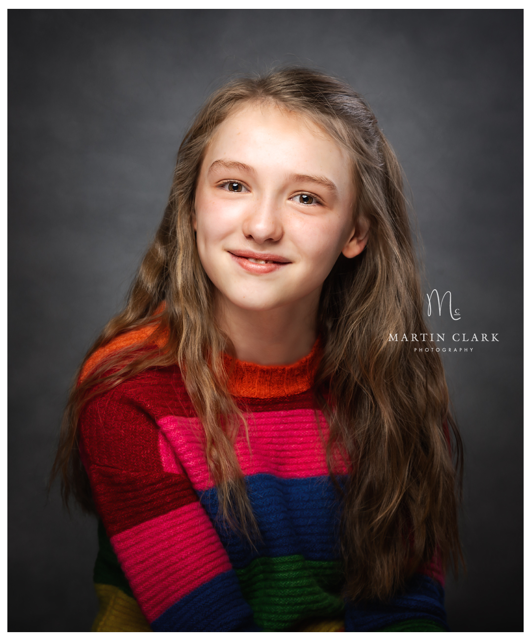 a happy portrait of a teenage girl wearing a striped sweater