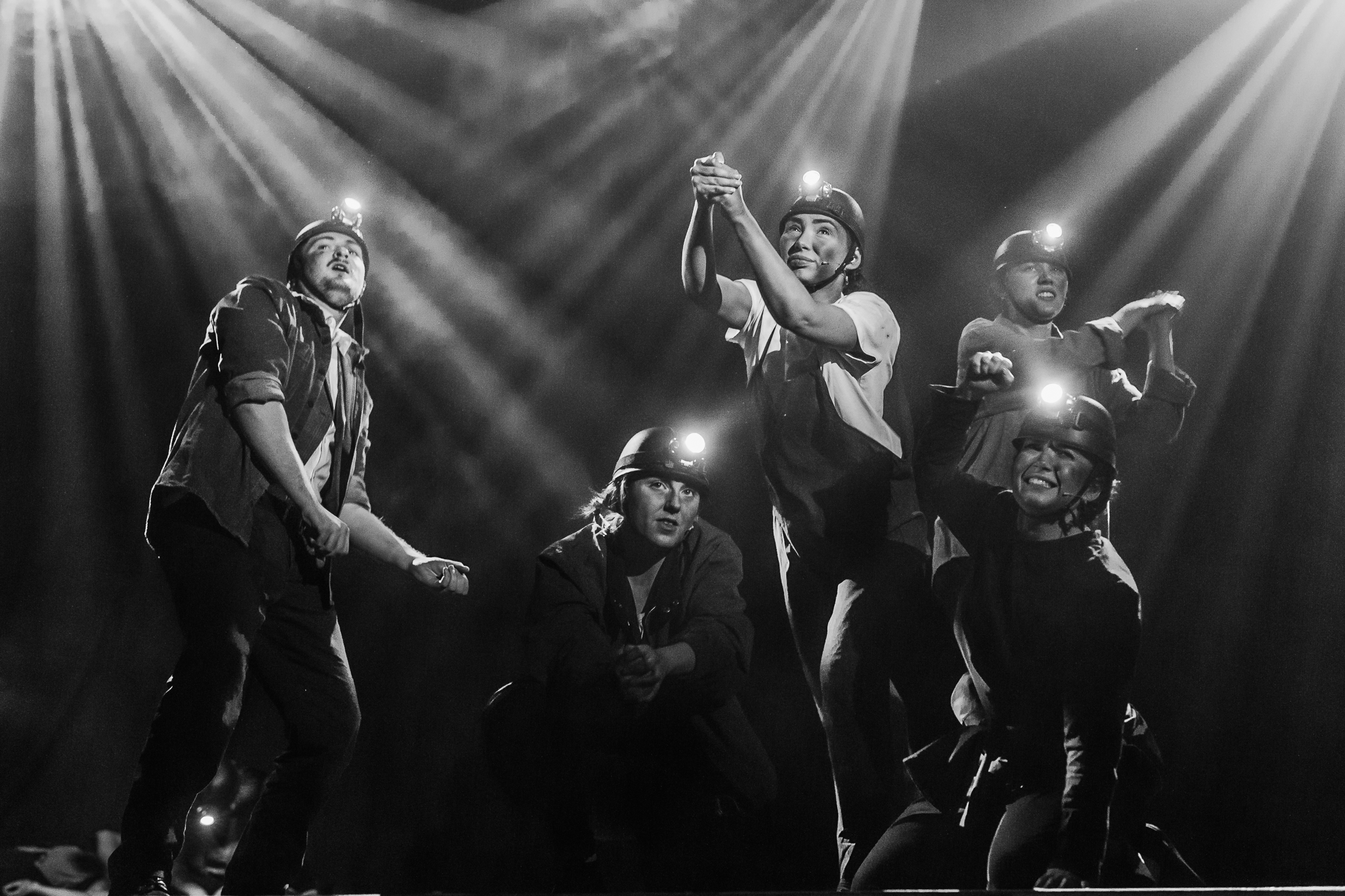 Stage theatre performance with dramatically lit coal miners