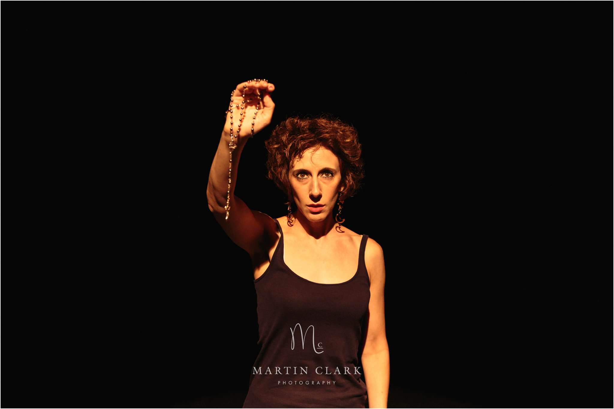 Actress from Royal Conservatoire of Scotland stage performance holding a crucifix on a chain in a dramatic stage play