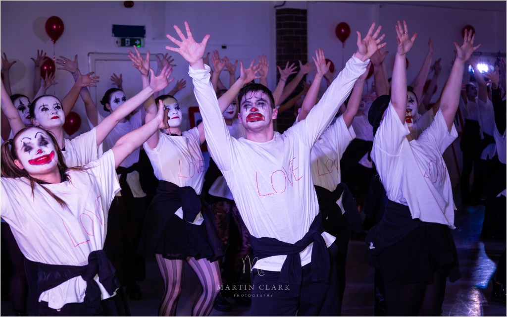 Sweaty dancer with clown face makeup with the word love written on his white shirt
