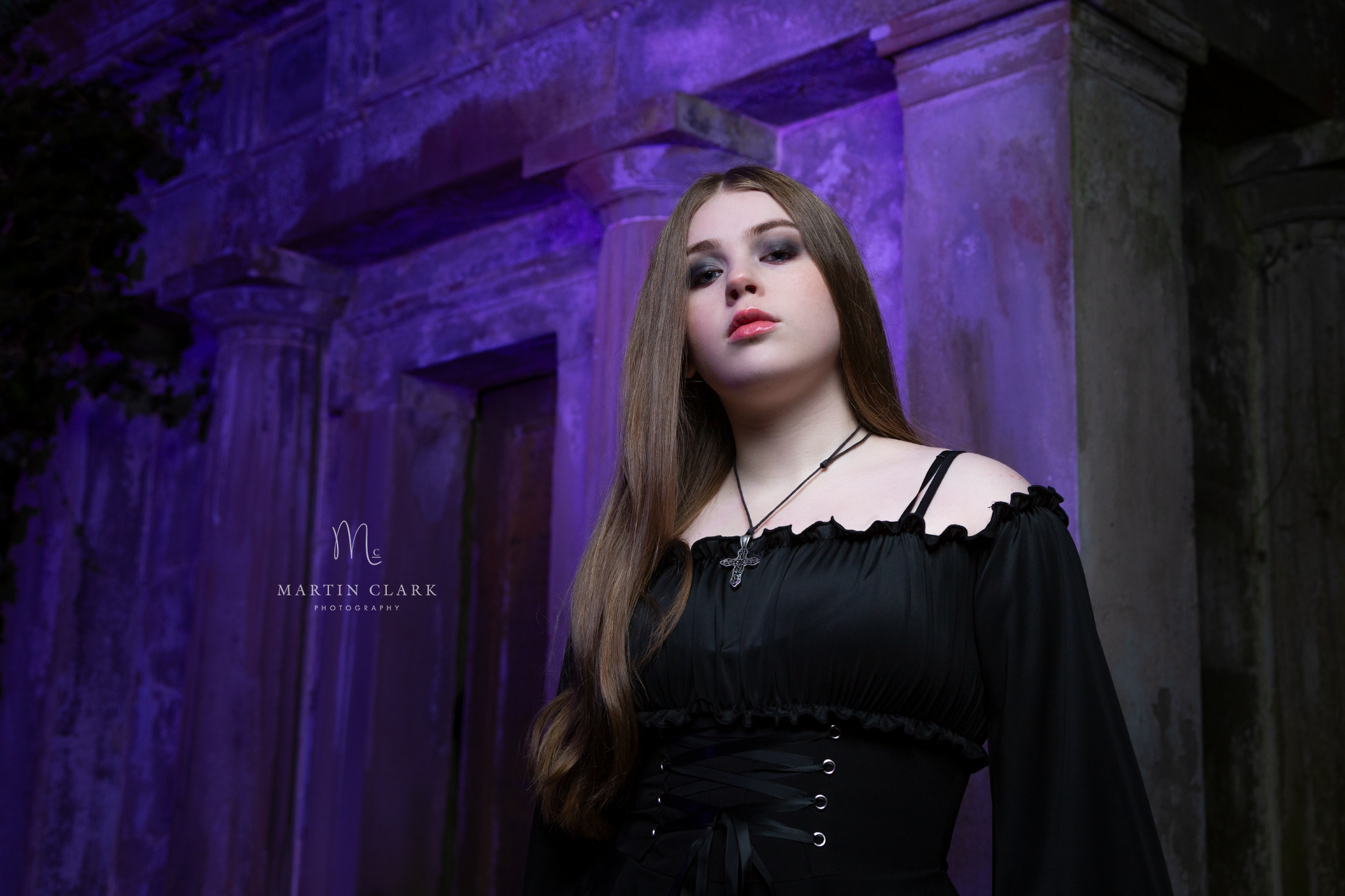 Young woman dressed in gothic costume standing beside a crypt in a graveyard