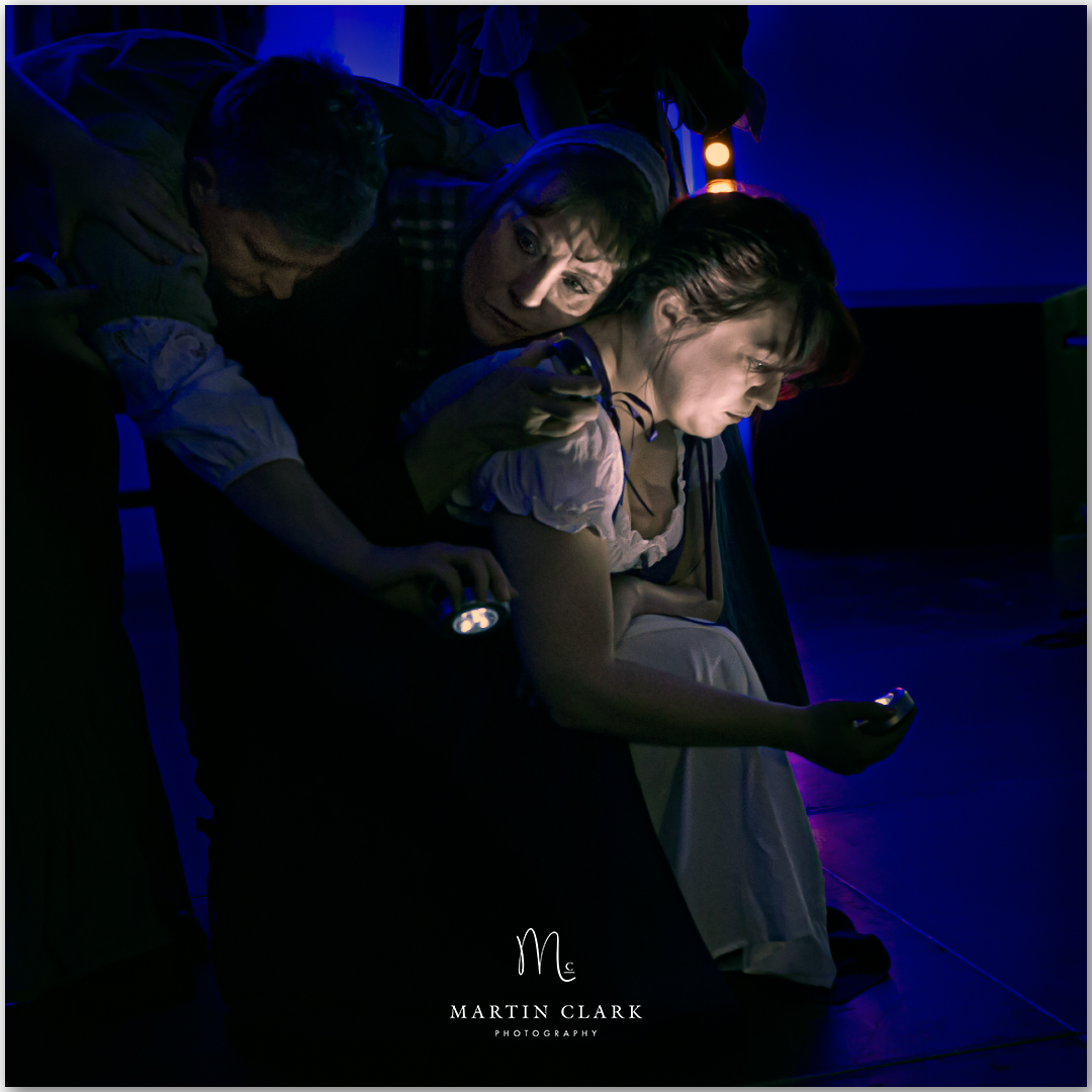 chiaroscuro image of theatre performance showing three actresses in period costume